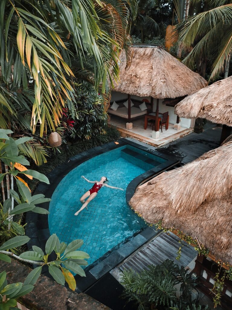Viaje de autor-leisure A woman enjoying leisure time floating in a tropical resort pool surrounded by lush greenery.